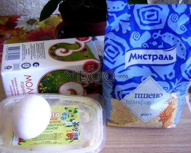 пачка пшена, упаковка молока, сливочное масло в пластиковом контейнере, куриное яйцо лежат на кухонном столе