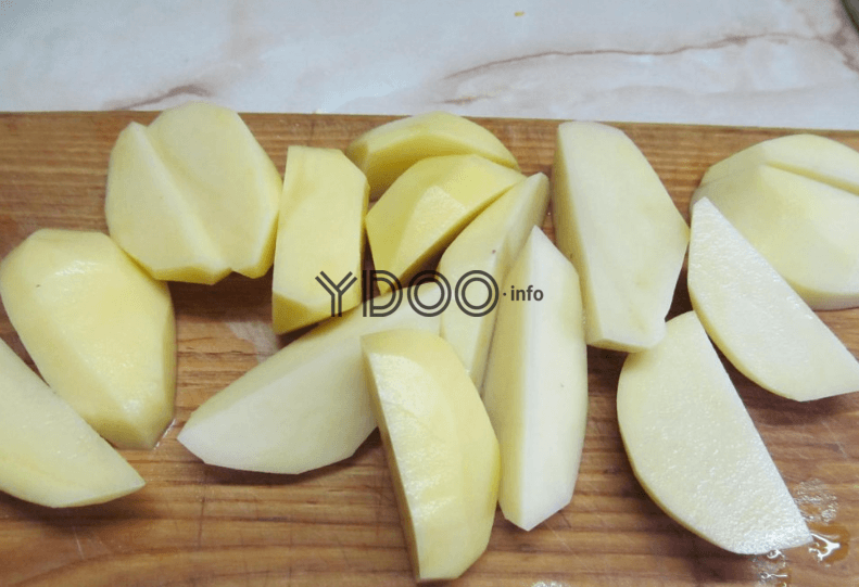 очищенные картофельные дольки на деревянной доске